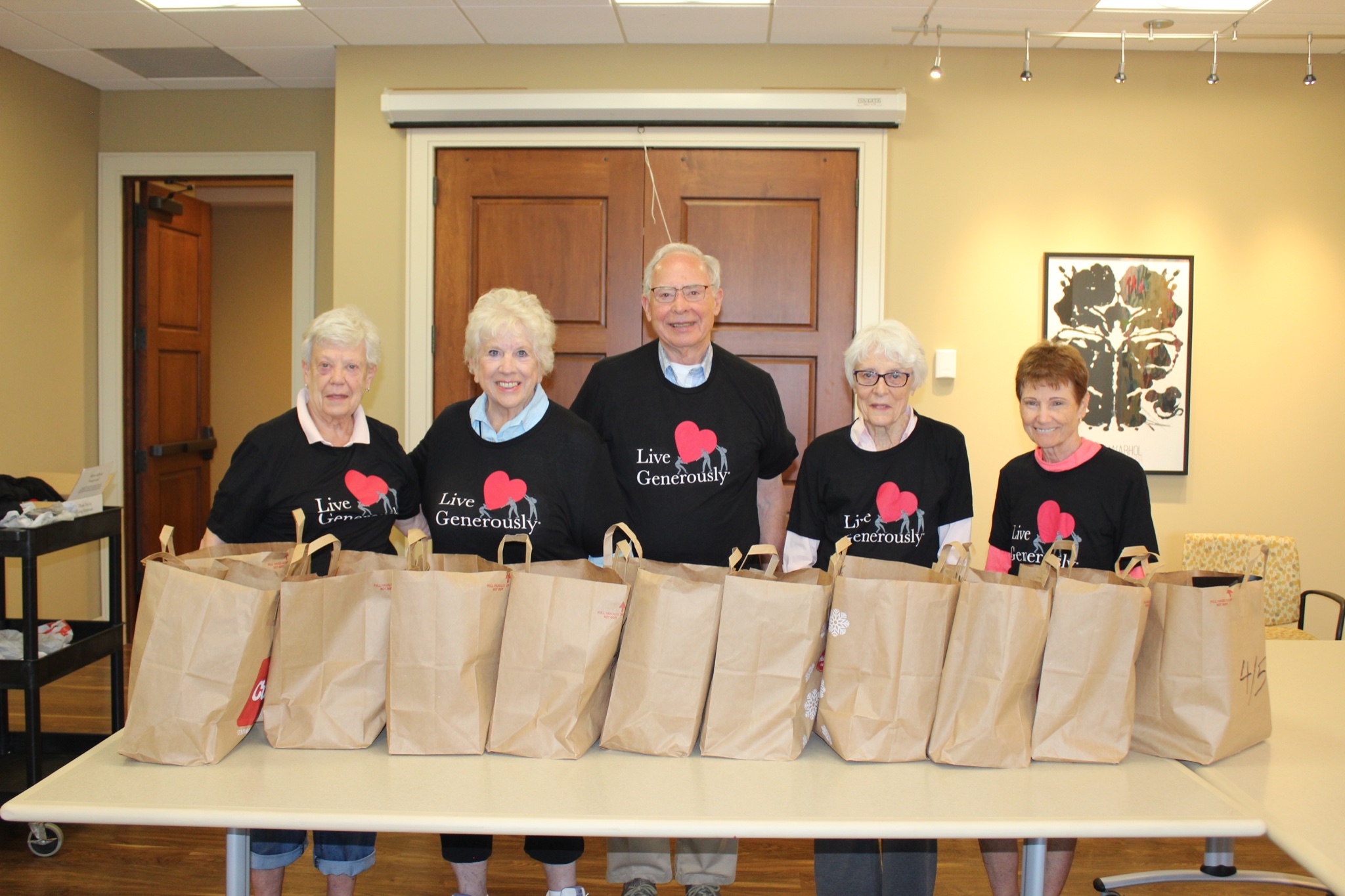 Senior residents collect food in paper grocery bags.