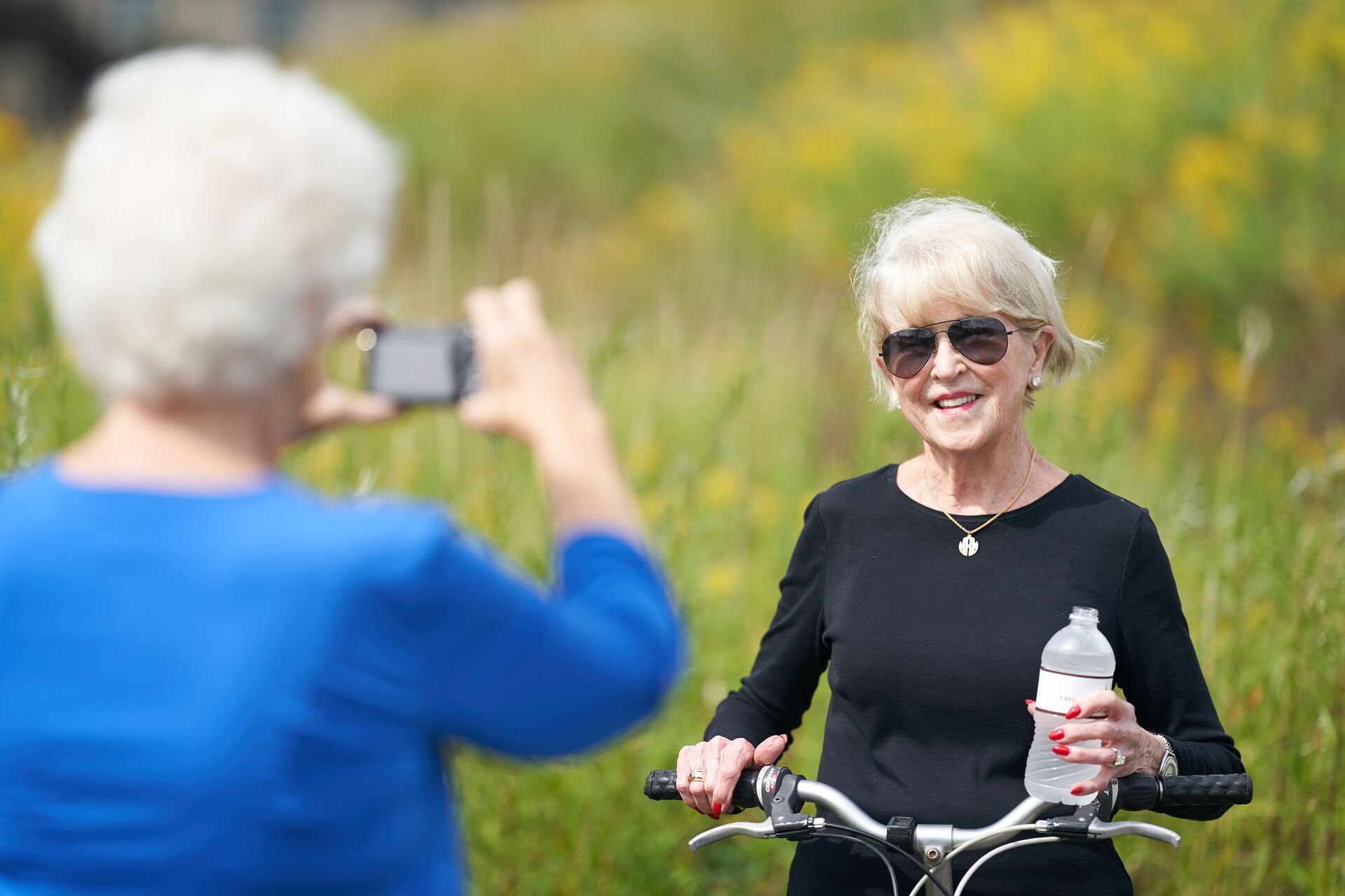 A senior woman poses with her bicycle for a picture while on a bike ride.